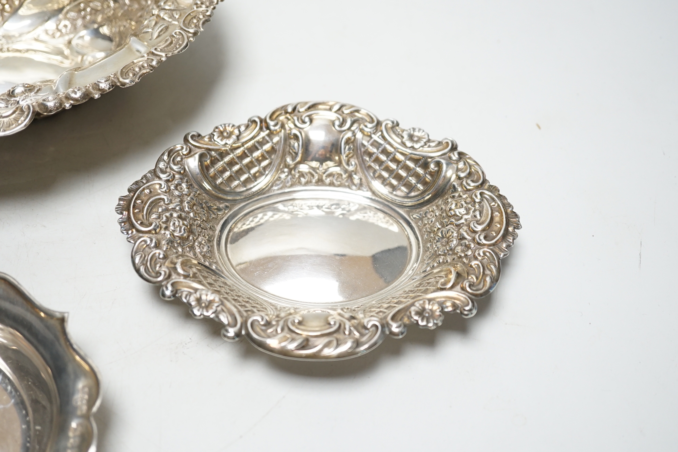 A late Victorian repousse silver oval bowl, William Comyns, London, 1889, 21.1cm and two other smaller silver dishes, 10.8oz.